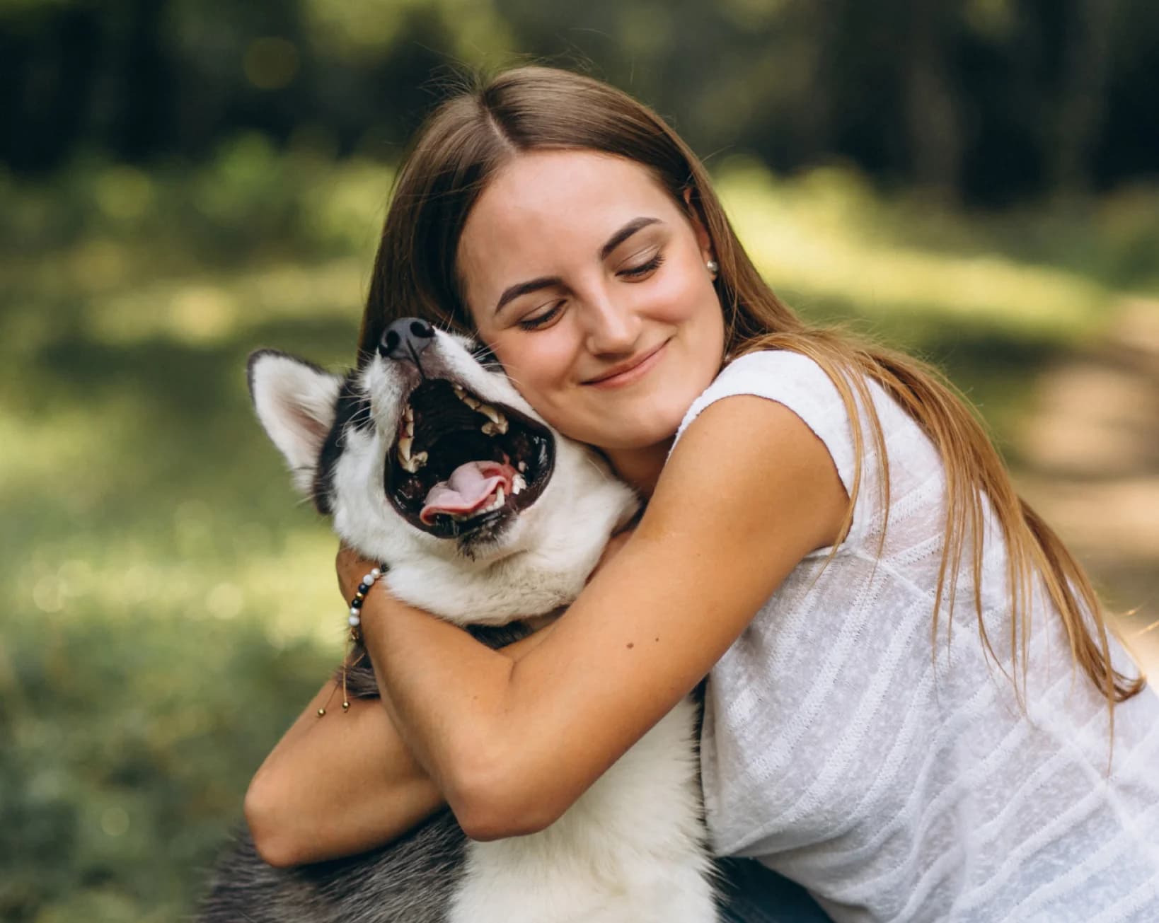 Woman hugging her husky in a garden